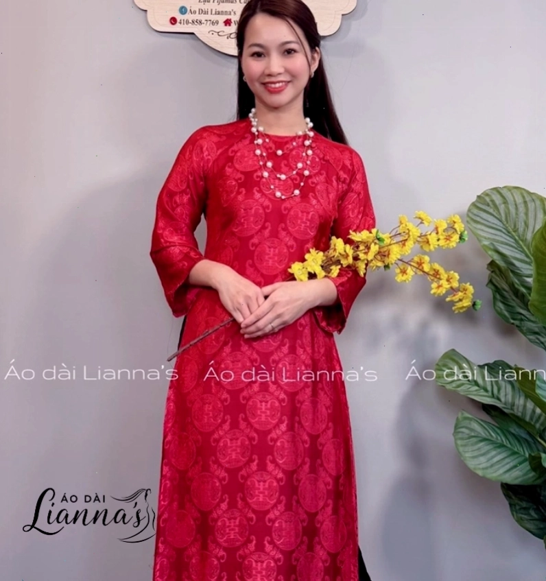 Người mẫu trẻ trung diện áo dài gấm cách tân màu xanh ngọc bích, phối cùng quần lụa trắng và túi xách nhỏ.