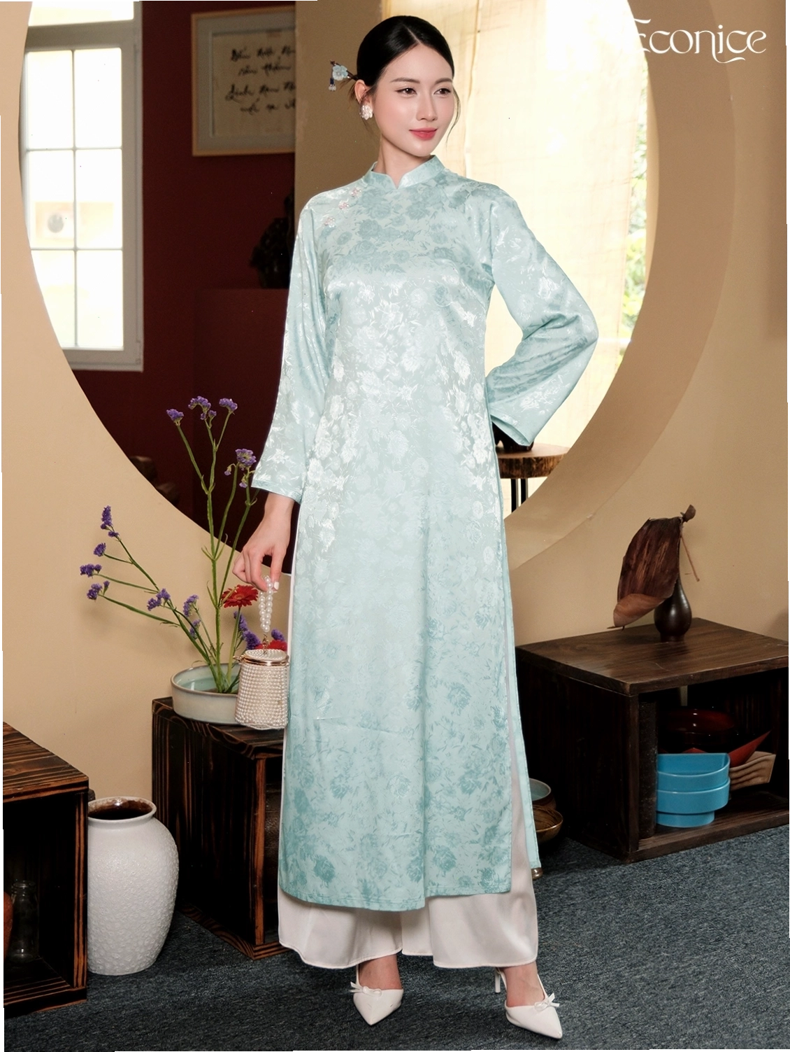 Set áo dài cách tân cổ thuyền, tay lỡ, gam màu xanh lá cây đậm, họa tiết lá cọ, phối cùng quần lụa đen.