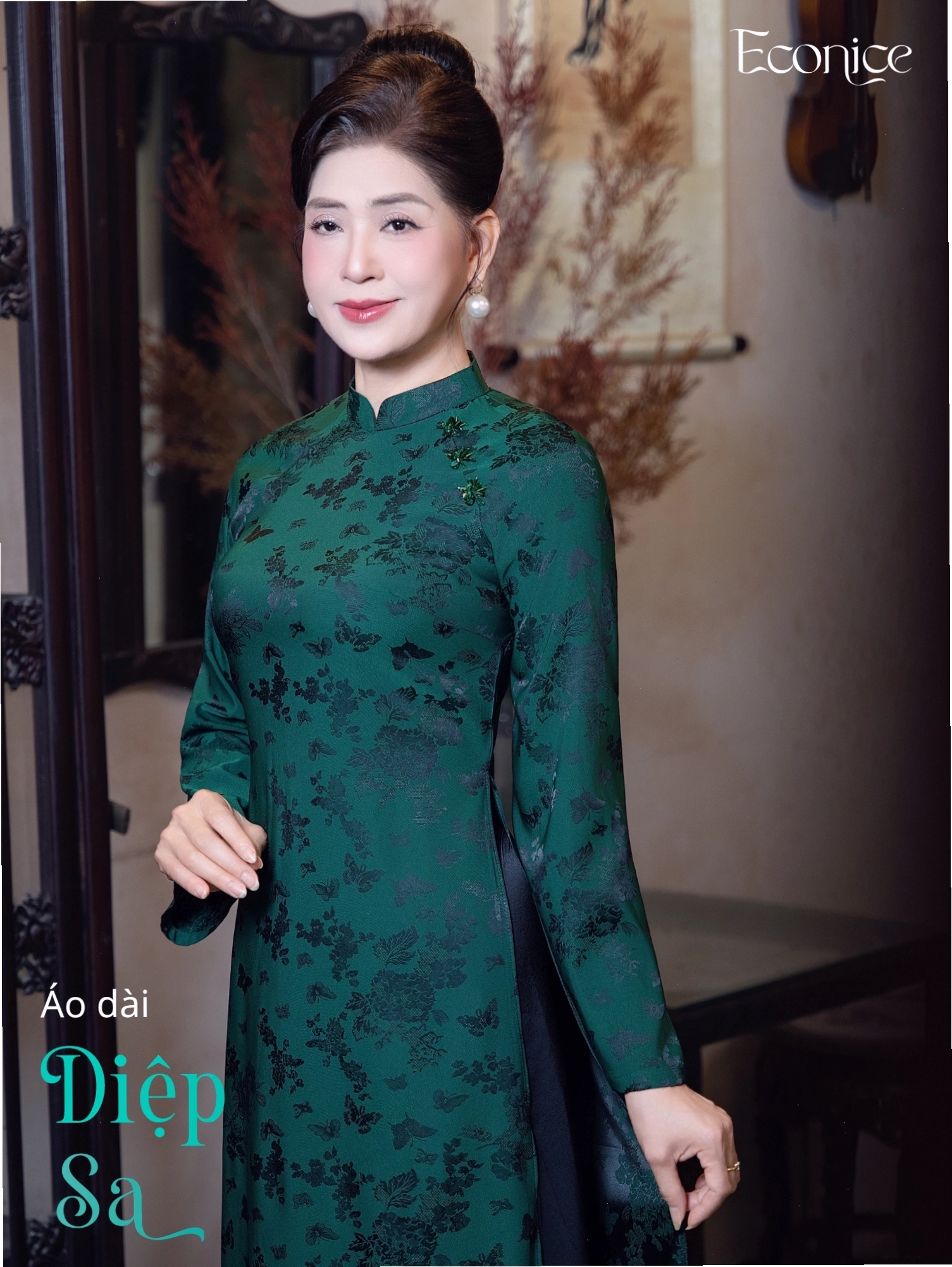 Set áo dài cách tân màu xanh ngọc bích, cổ thuyền, tay lỡ, phối cùng quần lụa trắng.