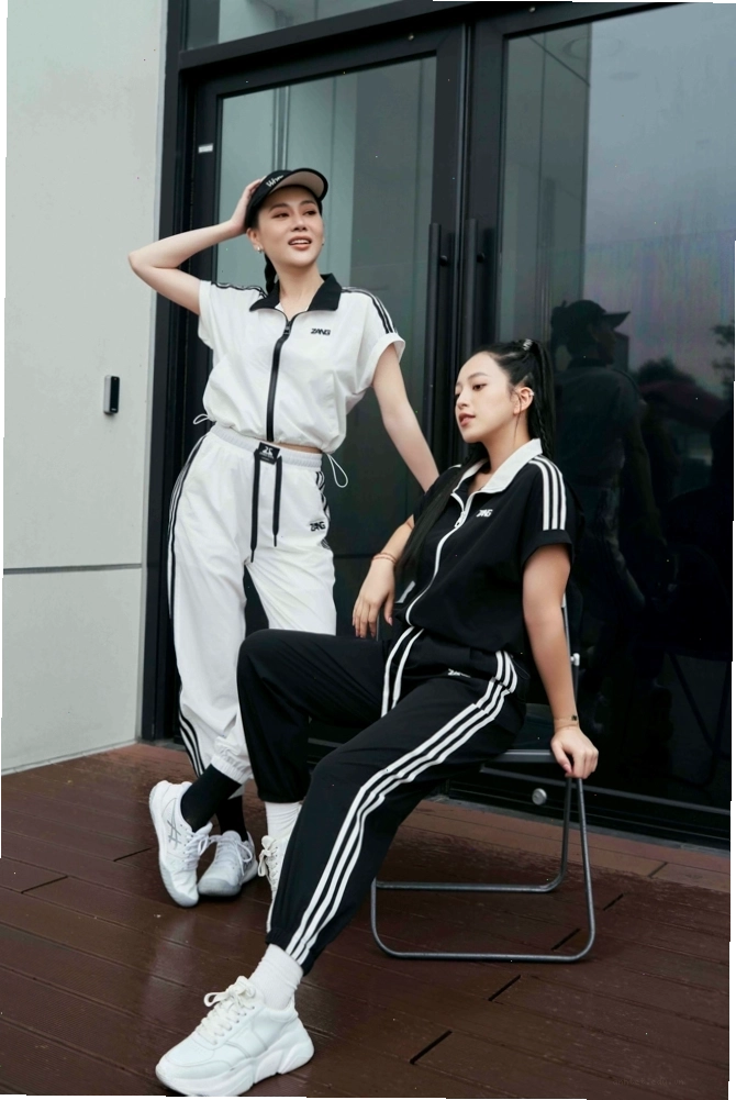 Set đồ thể thao nữ tay dài gồm áo hoodie xám và quần jogger xám, phối cùng giày sneakers trắng