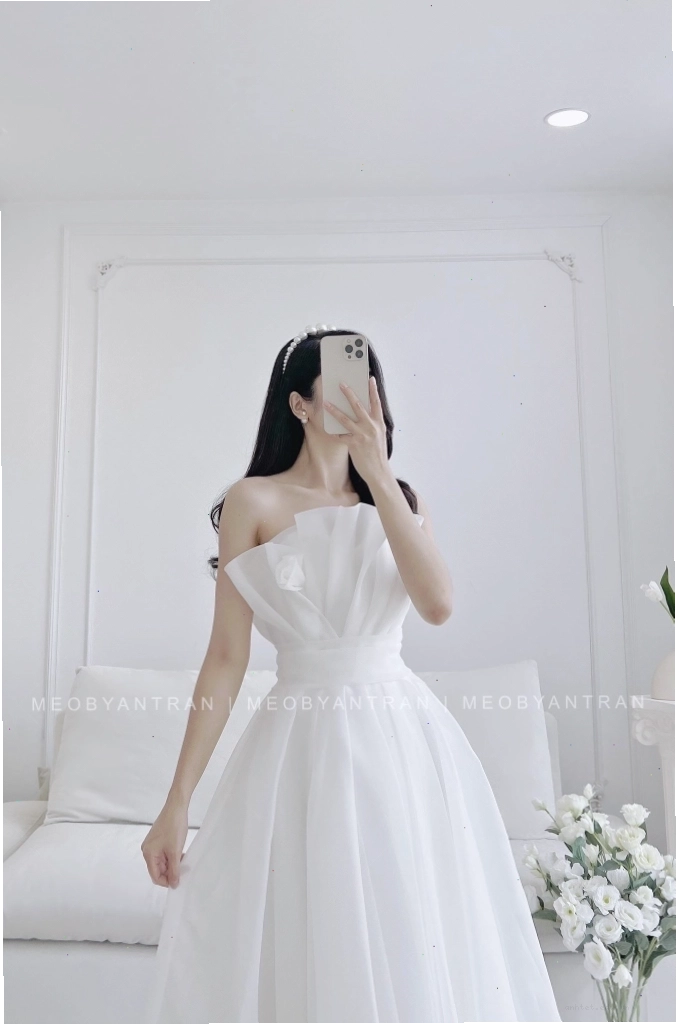 Váy voan dáng midi màu hồng pastel, cổ vuông, tay bồng, chân váy xòe nhẹ, điểm nhấn là những đường viền ren tinh tế
